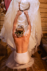 The bride puts on her dress. Naked model dresses in white dress.