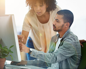Putting all their expertise into the project. designers talking together at a workstation in an...