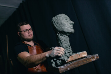 Man sculptor creates sculpt bust clay human woman sculpture. Statue craft creation workshop.