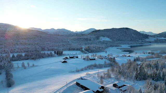Beautiful winter landscape filmed with a drone at Fylling, &Aring;lesund, Norway. In the distance we see several farms. The sun barely peeks over the mountain and creates a great atmosphere