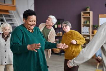 Portrait of black senior woman dancing in retirement home and smiling happily, copy space