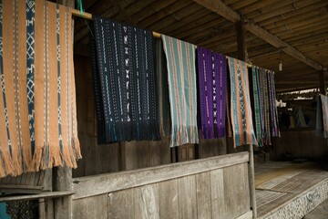 The traditional Bena Village on Flores, in focus traditional sarongs hanging in front of a hut.