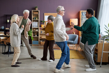 Full length view at group of senior people dancing in retirement home interior and enjoying activities - obrazy, fototapety, plakaty
