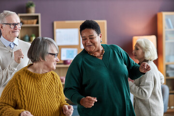 Waist up portrait of black senior woman dancing with friends in retirement home and smiling joyfully - Powered by Adobe