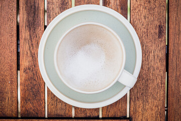 cup of coffee with foamed milk from above on wooden table