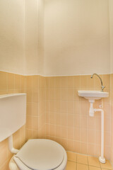 a toilet and sink in a small bathroom with tile on the walls, white fixtures and beige flooring...