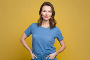 Obraz premium Beautiful caucasian girl standing on a yellow background looking at the camera. AI generative