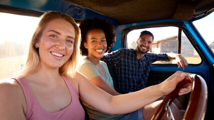 Portrait Of Group Of Friends On Road Trip Driving In Cab Of Pick Up Truck