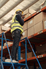Warehouse workers in a large warehouse Climb the ladder to inspect the goods on the top shelves.