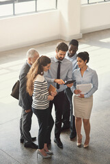 Fototapeta premium Running his plan by the team. High angle shot of a group of businesspeople talking together while standing in an office lobby.