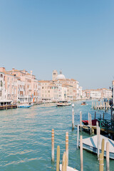 The great canal flows through Venice, taking its travelers with it. Everything shines in bright sunshine and the water shines turquoise.