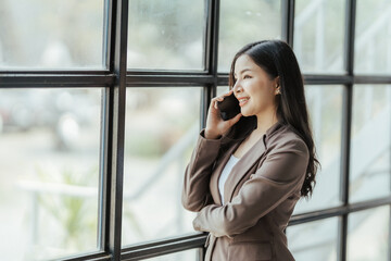 Asian businesswoman in formal suit in office happy and cheerful during using smartphone and working