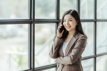 Asian businesswoman in formal suit in office happy and cheerful during using smartphone and working