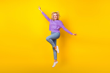 Fototapeta na wymiar Full size photo of pretty young girl jumping spread hands wings fly plane wear trendy purple clothes isolated on yellow color background