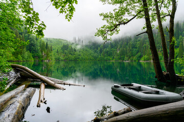 The rubber boat in the tropical forest the background of lake and green trees.