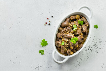Stewed chicken hearts with parsley, onions, say sauce. Top view, copy space, flat lay.