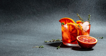 refreshing alcoholic cocktail with Sicilian red oranges, Aperitif on a dark background. Long banner...
