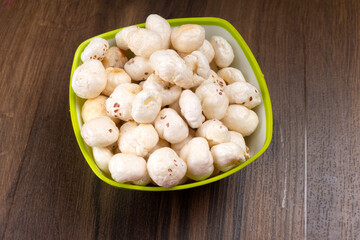 Organic Crispy Lotus pops Seeds or Phool Makhana served in a wooden bowl on background.