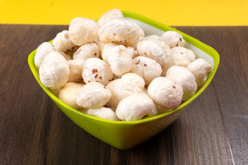 Organic Crispy Lotus pops Seeds or Phool Makhana served in a wooden bowl on background.