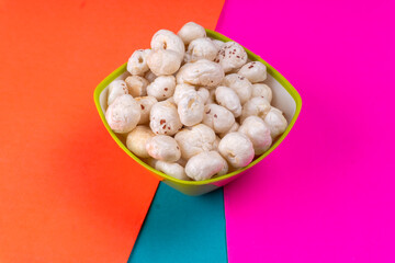 Organic Crispy Lotus pops Seeds or Phool Makhana served in a wooden bowl on background.