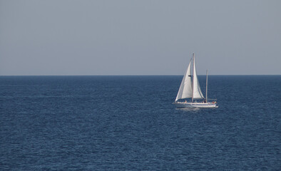 Velero navegando en el horizonte en Gallipoli, Italia. Yate con las velas desplegadas navengando en las aguas turquesas del mar Jónico.