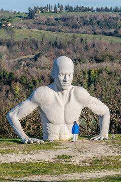 The Naturaliter giant, “Presenze” in the Fonte Mazzola amphitheater in Peccioli, Pisa, Italy, with a child in front of him who observes him from below