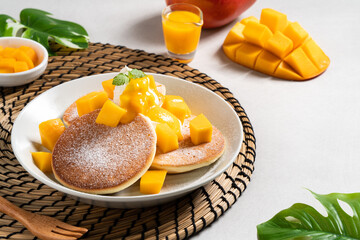 Delicious Japanese souffle pancake with dice mango and jam on gray table background.