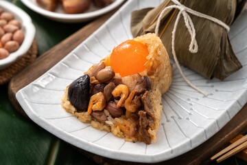 Zongzi. Rice dumpling for Dragon Boat Festival on green leaf background with ingredient.