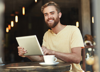Whats happening on social media. Portrait of a young man using a digital tablet in a cafe.