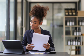 Attractive african american businesswoman working with tablet and documents on office desk.