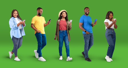 Obraz premium Glad young african american women and men in casual typing on smartphones, internet surfing