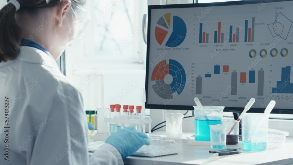 Poster a female researcher sits at a workplace in a laboratory, behind a personal computer monitor. against