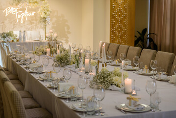 Table setting. Wedding banquet decoration in hall restaurant. Wedding setup. Luxury wedding reception. Festive arch decorated composition flowers and candles. Table covered a tablecloth in party area.