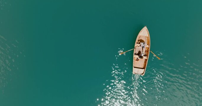 Aerial drone shot of a boat paddling in the blue lake, Lago di Braies, Italy, Dolomites