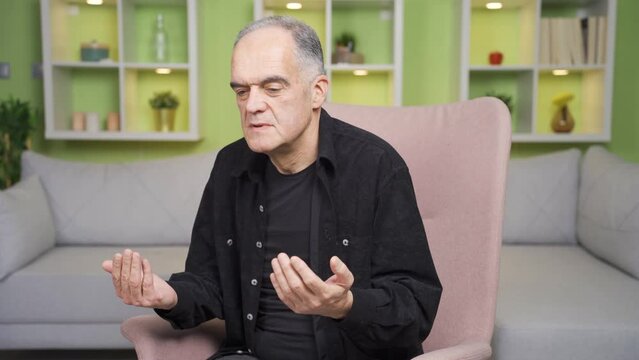 Praying old man. He raises his hands up and prays to God.
The old man, alone at home, prays. Amine.
