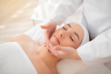Fototapeta na wymiar Beautiful indian female relaxing during face lifting massage in spa