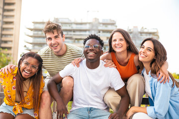 Group of five multiracial friends laughing and having fun outdoors - Cheerful young people laughing together at city - Friendship concept.