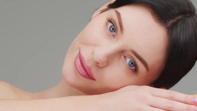 Fit European female beauty model puts her head on her hand while lying and looking at the camera on a white background. The concept of skin protection and female beauty