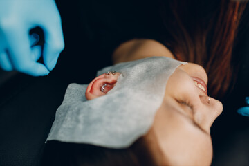 Young woman doing ear piercing at beauty studio salon