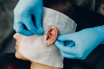 Young woman doing piercing at beauty studio salon - 579017488