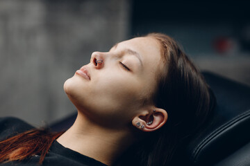 Young woman doing piercing nose ring at beauty studio salon