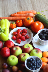 Berries in vintage porcelain dishes, other healthy fruit and vegetable on wooden table. Selective focus.