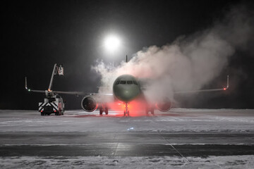 Ground deicing of a passenger airplane on the night airport apron at winter