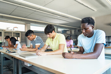 Teenager Students doing a written exercise at High School - Focus on African Man