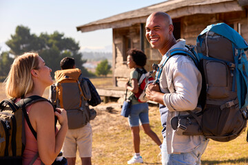 Group Of Friends With Backpacks Hiking In Countryside Together