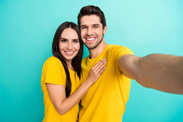 Photo of shiny charming husband wife dressed yellow t-shirts hugging smiling tacking selfie isolated turquoise color background