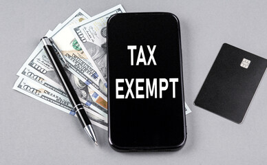 Credit card and text TAX EXEMPT on smartphone with dollars and pen. Business concept