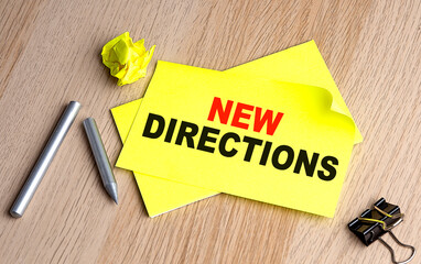 NEW DIRECTIONS text on yellow sticky on wooden background