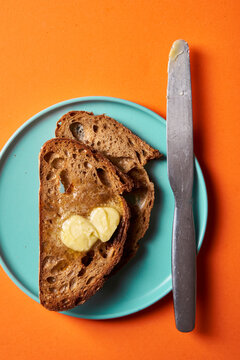 sliced bread with butter on blue plate with knfe