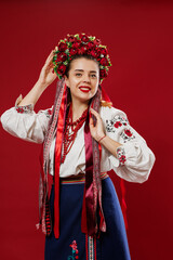 Portrait of ukrainian woman in traditional ethnic clothing and floral red wreath on viva magenta studio background. Ukrainian national embroidered dress call vyshyvanka. Pray for Ukraine